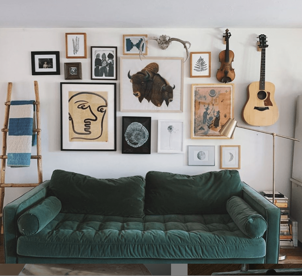 mur avec objets déco et instruments de musique et cadres au dessus de canapé vert