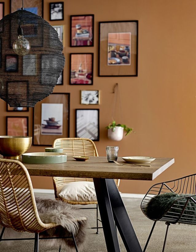mur de cadres de couleur de peinture chaude et ocre derrière table en bois et métal