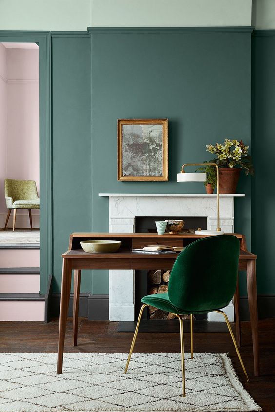 chaise vert émeraude et bureau en bois dans pièce aux murs verts