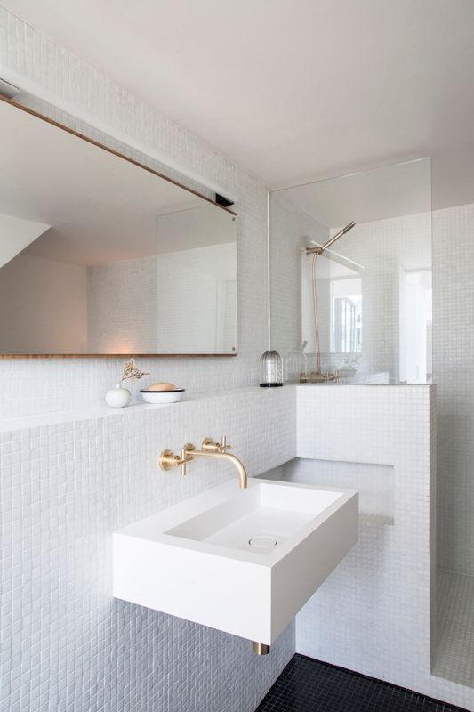 les murs de cette salle de bains sont entièrement couvert de mosaïque blanche pour un effet lumineux