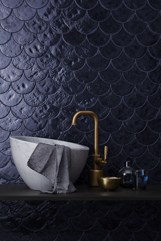 une salle de bains de caractère avec une vasque en marbre et de la robinetterie dorée sur mosaïque en bleu nuit