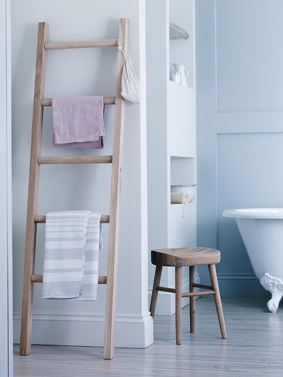 salle de bains en couleurs claires avec serviettes rangées sur échelle en bois