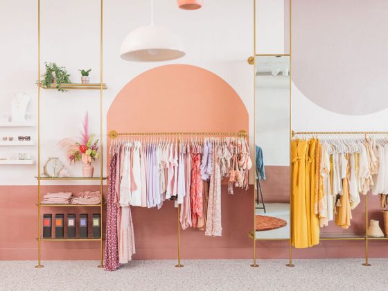 vêtements de couleurs sur portants en métal doré dans une boutique aux murs roses et saumon