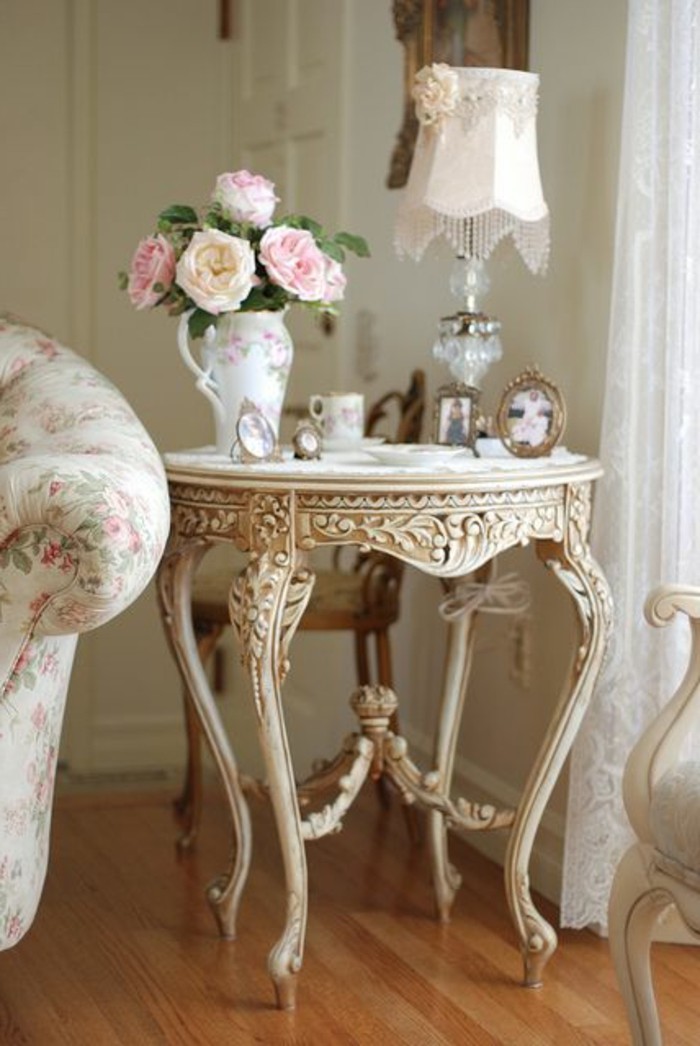 une table de style classique portant un vase avec des roses et des objets de déco shabby