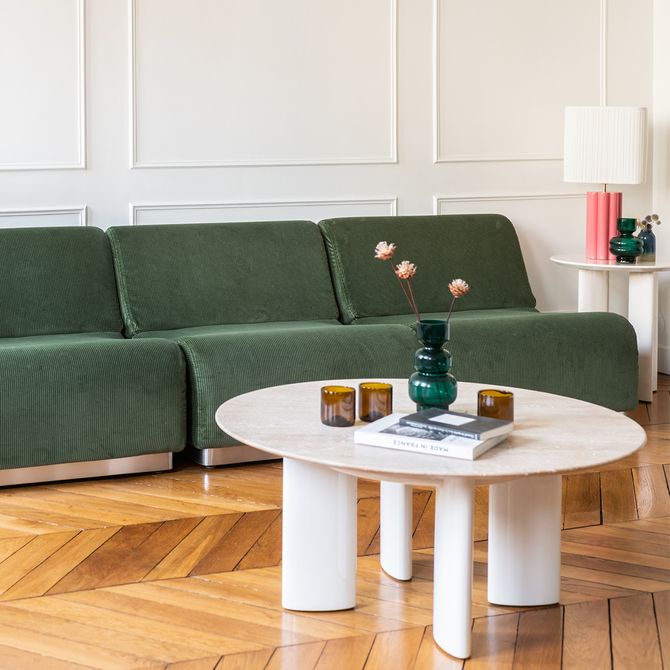 large canapé en velours vert avec une table basse ronde en marbre