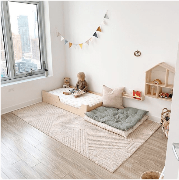 aménagement chambre bébé Montessori avec lit au sol sur un tapis à côté d'un espace de jeu