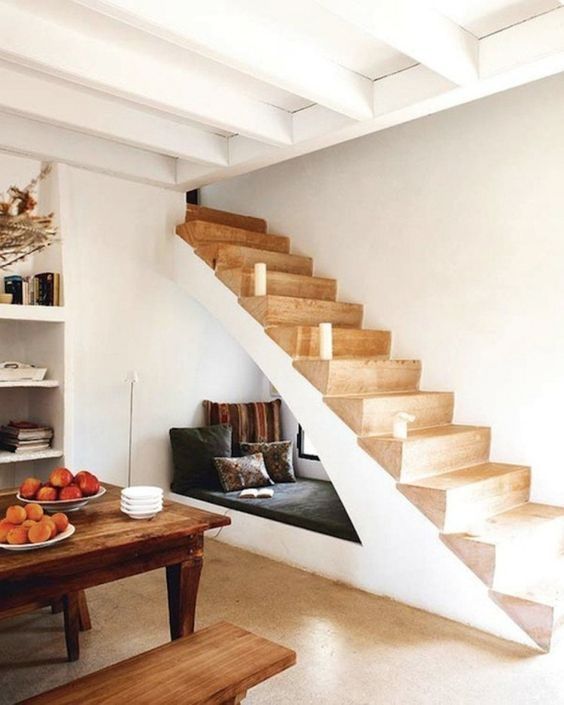 escalier en bois abritant un coin lecture cocooning dans une pièce blanche