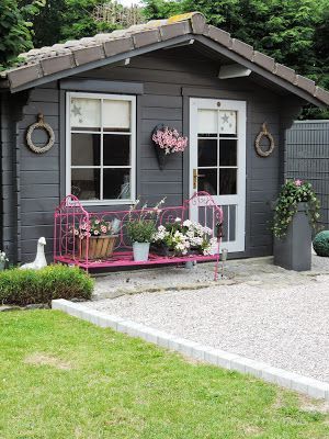 cabane de jardin grise style cottage anglais avec banc sur le porche et fleurs autour