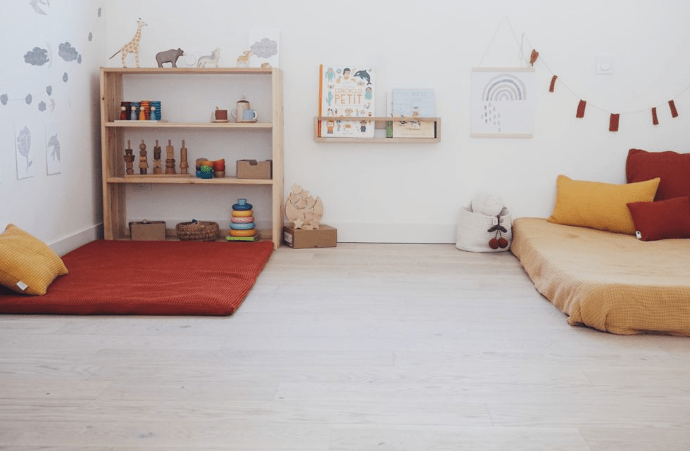 matelas et couvertures de couleurs chaudes sur le sol dans une chambre bébé Montessori