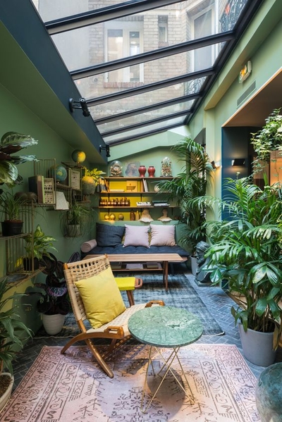 terrasse aménagé sous une verrière avec plantes d'intérieur et couleurs de nuances de vert