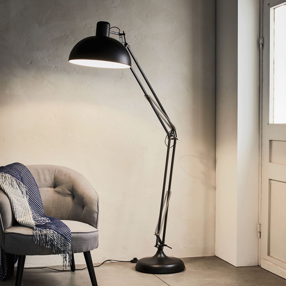 lampadaire format XXL de style industriel illuminant un fauteuil