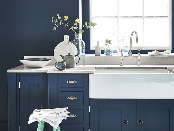 mobilier et mur en bleu foncé sous un évier en céramique blanc dans une cuisine bord de mer