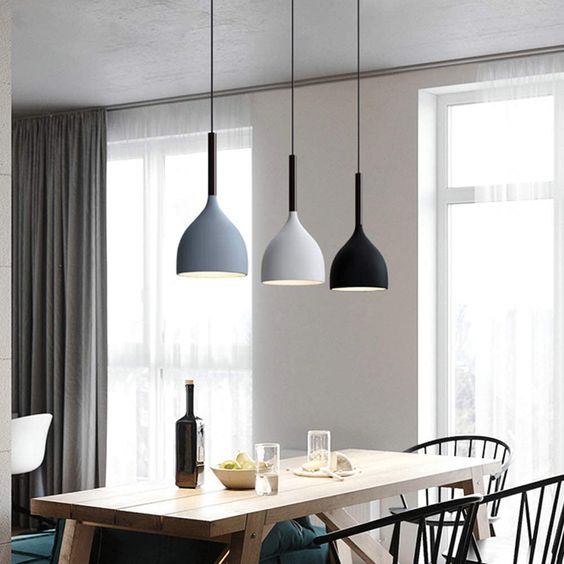 luminaires tendance en nuances de gris suspendus au dessus d'une table à manger en bois