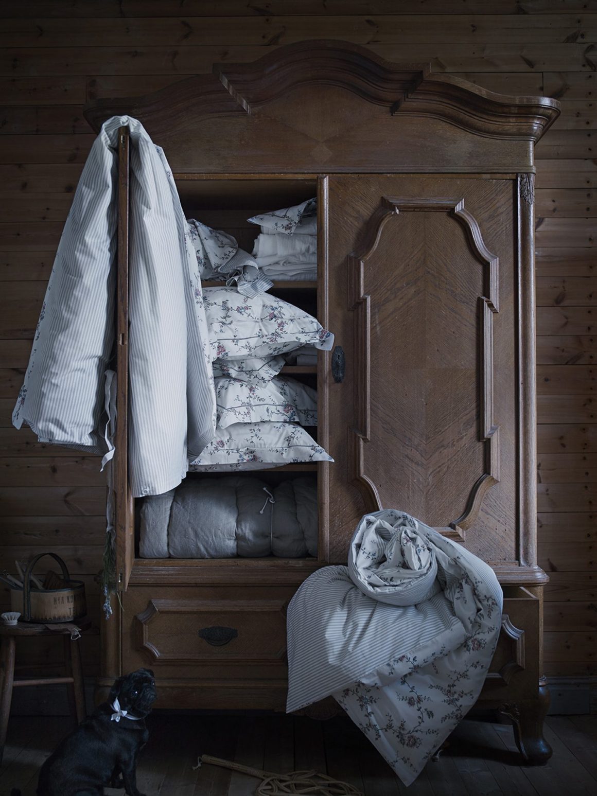 armoire rustique en bois foncé pour ranger des draps et des coussins fleuris