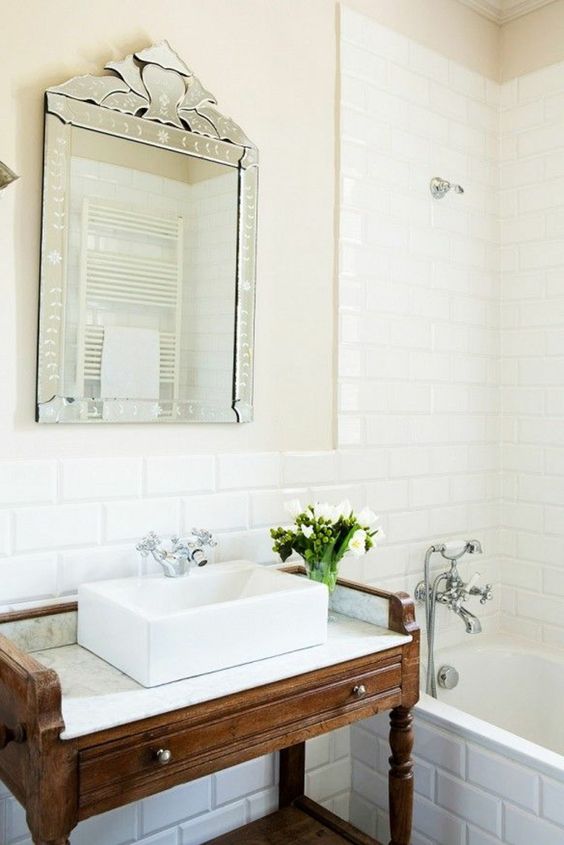 salle de bains en faïence blanc et vasque en céramique au dessus d'un meuble vintage en bois