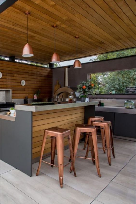 cuisine d'extérieur en bois de style industriel avec bar et chaises métalliques