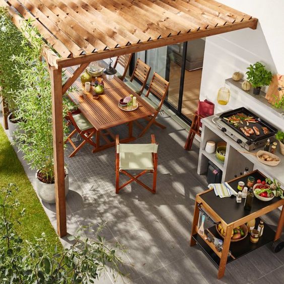 cuisine d'extérieur avec plancha et coin repas avec table et chaise en bois