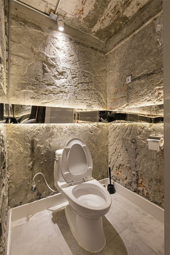 des toilettes blanches entourées de murs irréguliers en ciment