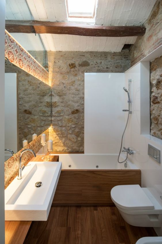 une salle de bains rustique avec un mur en pierre et un parquet en bois
