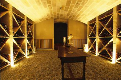 grand table en bois au milieu d'un aménagement cave à vin avec lumière tamisée