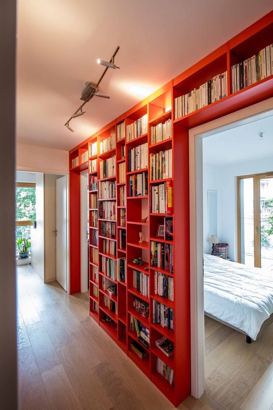 aménagement bibliothèque rouge en bois sur tout un mur de hall