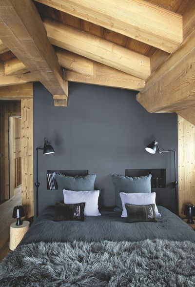 linge de lit et mur bleu pétrole dans une chambre au toit en bois