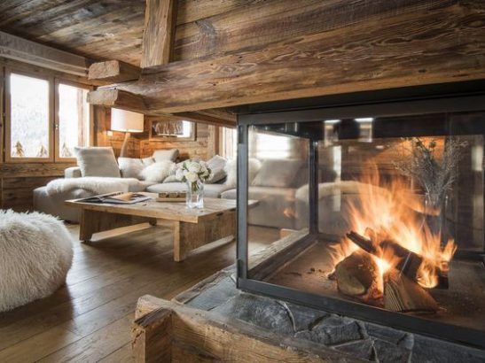 feu de bois dans une cheminée rustique en bois dans un grand salon douillet de chalet