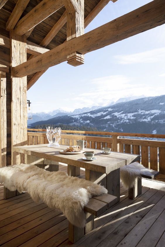 table et banc en bois sur terrasse de chalet avec vue sur montagne