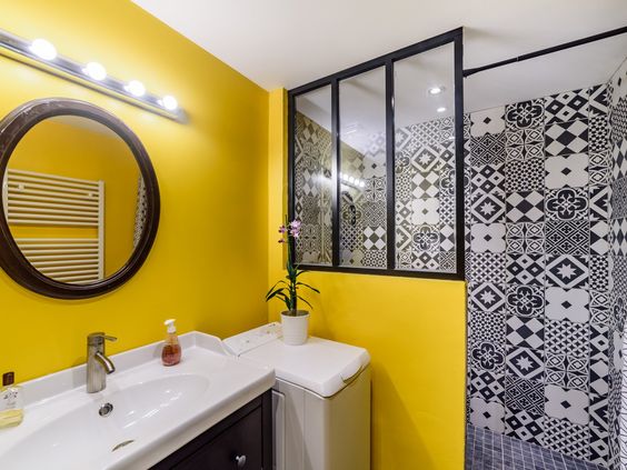carreaux géométriques noirs et blancs dans la douche d'une salle de bains colorée en jaune