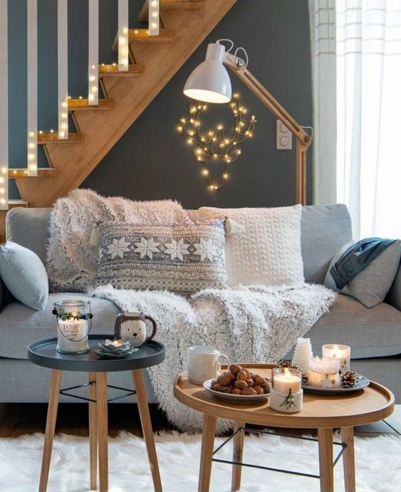 plaid et coussins sur un canapé gris dans un salon déco hivernale