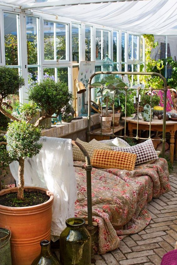 lit vintage avec coussins et plaids dans une véranda colorée déco jardin d'hiver