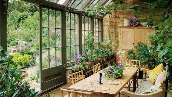 table à manger entourée de plantes et fleurs en déco jardin d'hiver