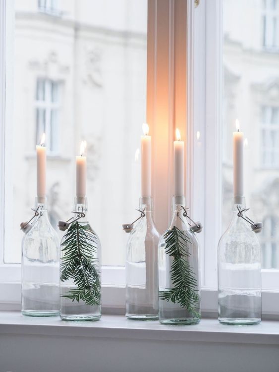 déco lumineuse Noël avec bougies et branches de sapin dans bouteilles en verre