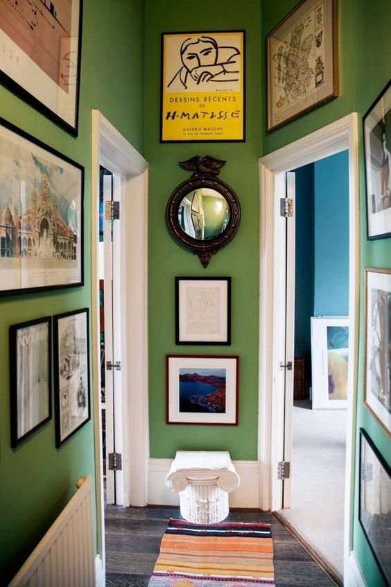 aménagement couloir peint en vert avec cadres et miroirs aux murs