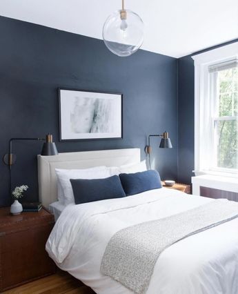 mur bleu nuit derrière un lit blanc pour réussir une déco chambre moderne