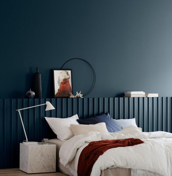 mur et tête de lit peints en bleu nuit dans une chambre moderne avec mobilier design