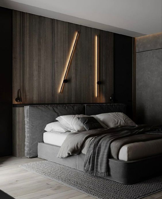 chambre contemporaine avec néons dorés accrochés au mur en bois derrière un lit gris avec linge en blanc