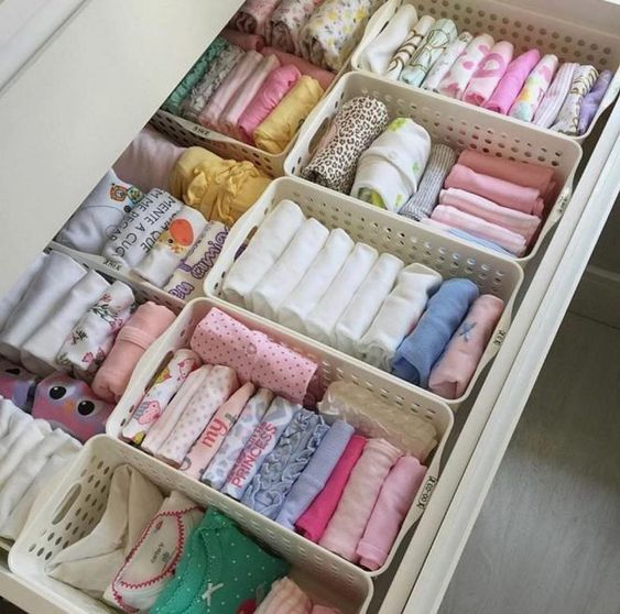 affaires bébé rangés dans des casiers en plastique disposés dans un tiroir