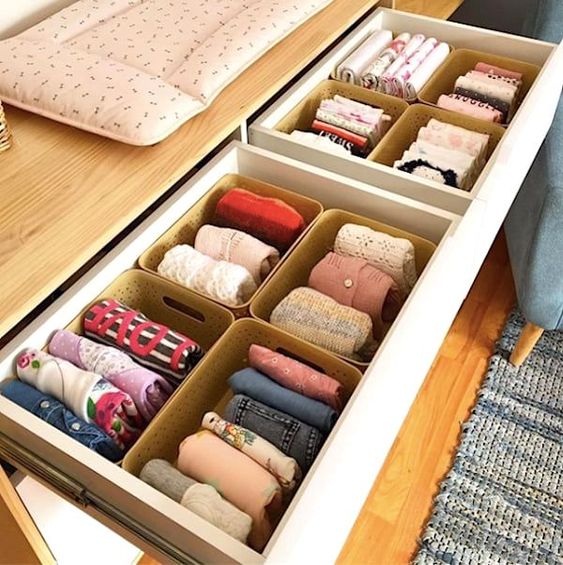 vêtements de bébé rangés dans des casiers en plastique à l'intérieur d'un tiroir