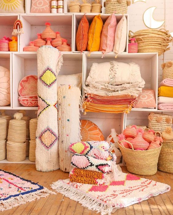tapis et coussins roses et oranges rangés dans des caisses en bois