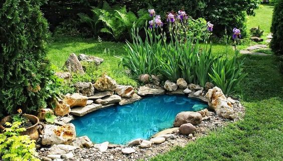 eau turquoise dans un bassin d'eau entouré de galets dans un jardin fleuri