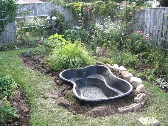 installation de la cuve en polyéthylène d'un bassin d'eau dans un jardin