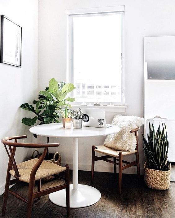 coin repas d'angle avec plantes décoratives autour d'une table blanche ronde et des chaises vintage