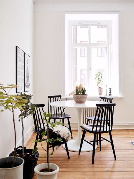 chaises noires en bois autour d'une table blanche ronde dans un coin repas d'angle