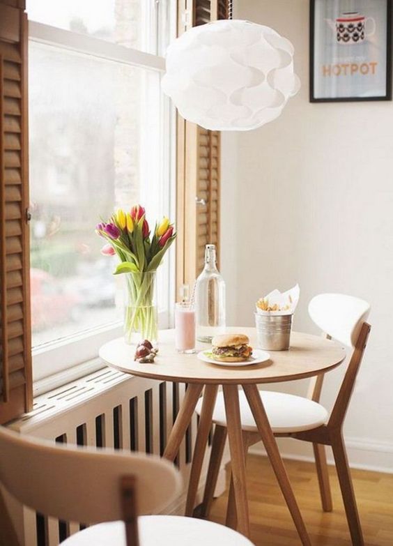 table de repas ronde et chaises en bois devant une fenêtre de cuisine