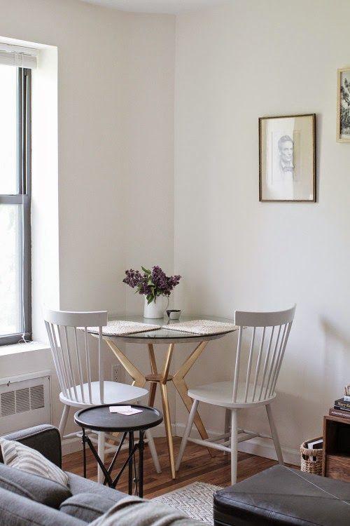 coin repas d'angle dans un séjour avec table ronde en verre et chaises classiques en bois