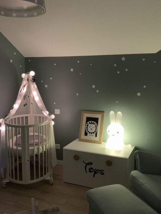luminaire chambre bébé doux avec veilleuse sous forme de lapin sur la commode et des guirlandes lumineuses au dessus du lit