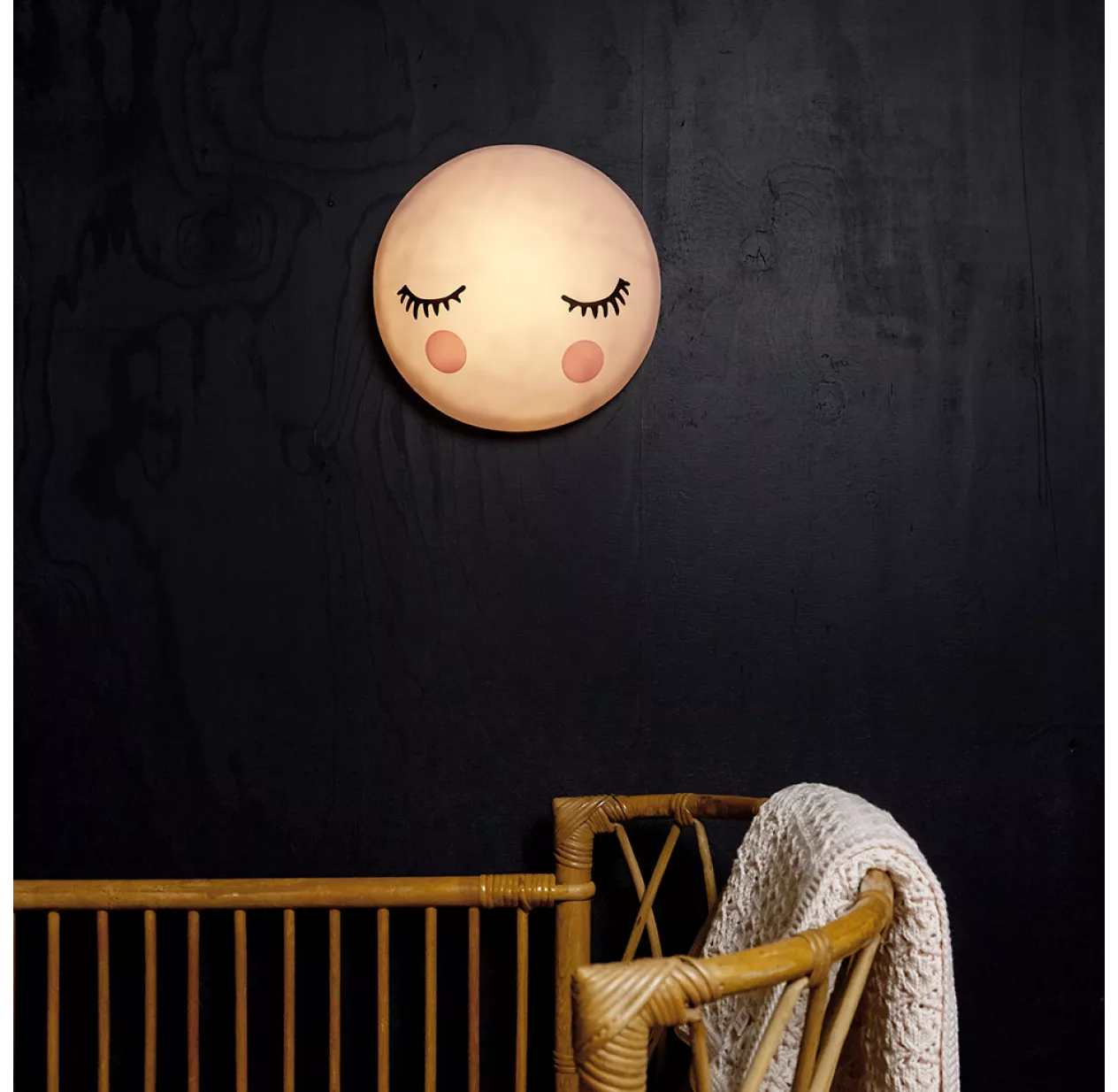 veilleuse pour bébé sous forme de lune accrochée à un mur noir derrière lit bébé