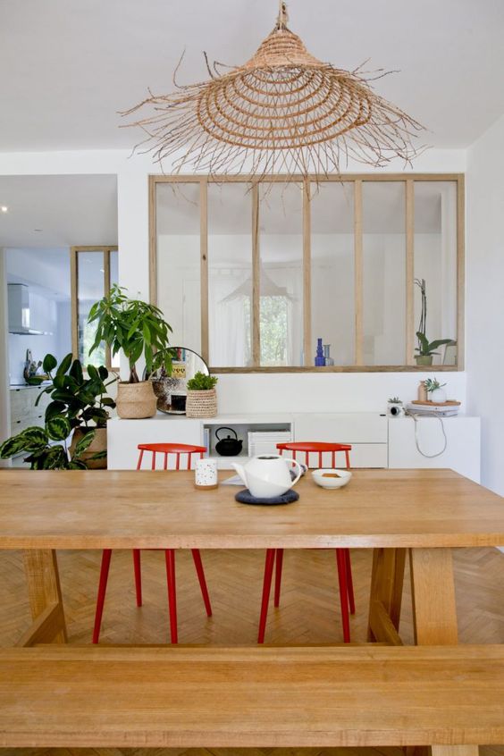 salle à manger avec table en bois massif séparée de la cuisine par une verrière intégrée au mur