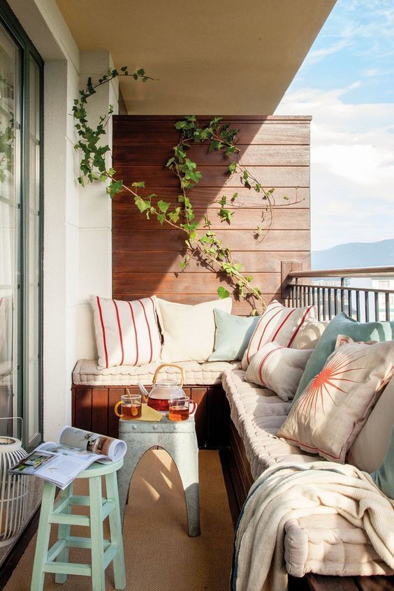 matelas et coussins sur un canapé d'angle en bois pour aménager un balcon en longueur